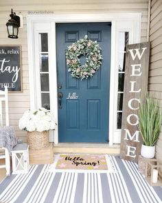 a blue front door with a welcome mat and potted plants on the porch next to it