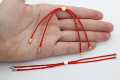 a hand is holding two red string bracelets