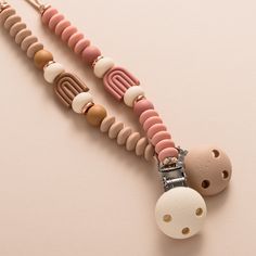 two pacifiers are attached to a necklace on a pink surface with white and brown beads