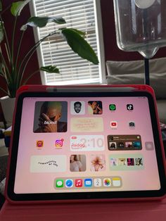 an ipad is sitting on top of a red table in front of a potted plant