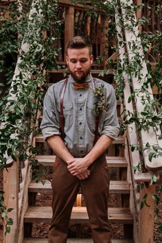 a man in suspenders and bow tie standing on steps with his hands behind his back