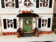 a doll house decorated for halloween with pumpkins and wreaths on the front door