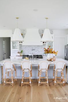 a kitchen with white cabinets and chairs around the counter top, along with an island