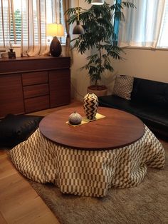 a living room with a couch, coffee table and potted plant in the corner