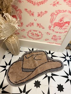 a bathroom rug with a cowboy hat on the floor next to a potted plant