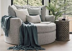 a living room with a round chair and pillows on the floor next to a potted plant