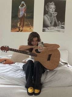 a woman sitting on top of a bed with a guitar in front of her face