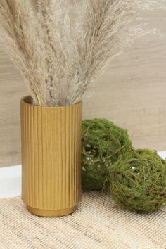 a plant in a gold vase next to some moss on a burlap cloth