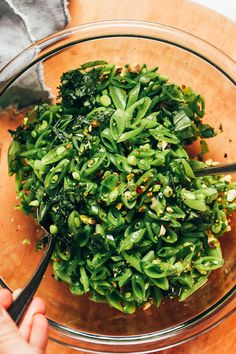 a bowl filled with green vegetables on top of a wooden table