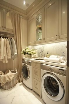 a washer and dryer in a small room with clothes hanging on the rack