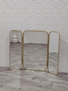 two mirrors sitting on top of a wooden floor next to a white and gray wall