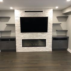 an empty living room with built in shelves and a flat screen tv above the fireplace