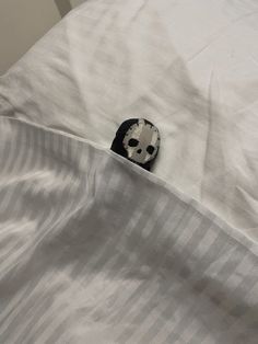 a black and white stuffed animal sticking out of the pocket of an unmade bed