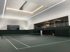 an empty tennis court with lights on the ceiling