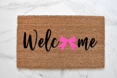 a welcome mat with a pink coffee cup on it and the words welcome written in black