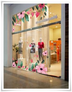 a window display with pink flowers and mannequins