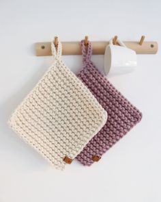 three crocheted purses hanging on a wooden hanger next to a cup