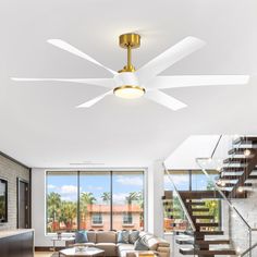 a living room with white walls and ceiling fan in the center, stairs leading up to second floor