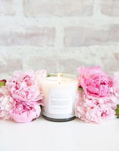 a candle with pink peonies around it