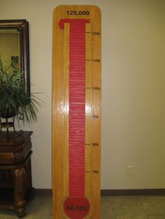 a tall wooden thermometer sitting next to a plant