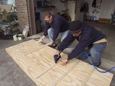 two men working on wood boards in a garage