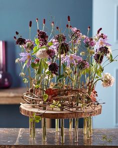 flowers in vases sitting on top of a wooden table next to a blue wall