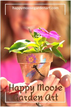 a woman holding a potted plant with flowers in it and the words happy mooe garden