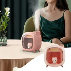 a woman sitting at a table in front of a pink toaster with a small bear on it