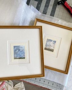 two framed pictures sitting on top of a table next to a pair of tape measures