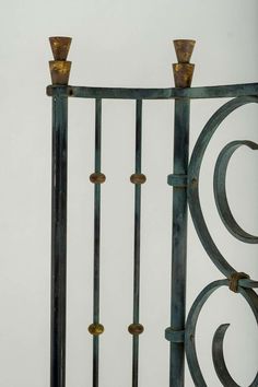 an iron gate with two candles on it and a white wall in the back ground