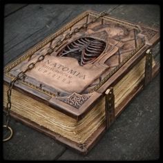 an old book with a skeleton on it sitting on a wooden floor next to a key