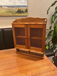 a wooden cabinet sitting on top of a table next to a potted green plant