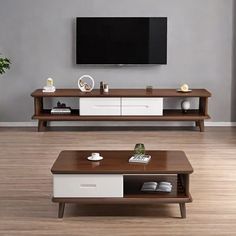 a living room with two coffee tables and a tv on the wall above it, in front of a gray wall