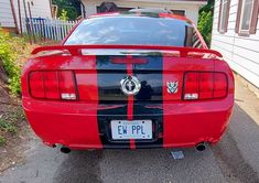 the rear end of a red sports car parked in front of a house