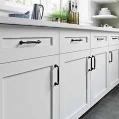 a kitchen with white cabinets and black flooring