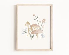 a framed print with mushrooms and flowers on the wall in front of a white wall