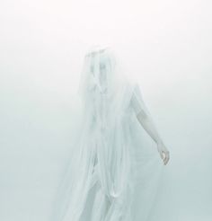 a woman dressed in white is walking through the fog