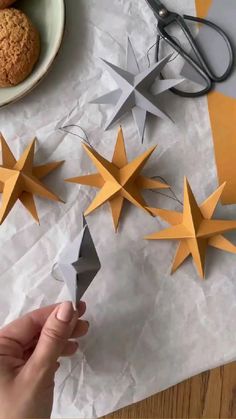 someone cutting out paper stars with scissors on top of the crafting supplies and cookies