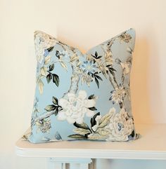 a blue floral pillow sitting on top of a white shelf