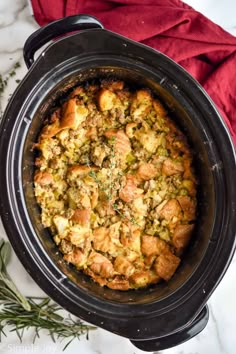 a crock pot filled with stuffing and vegetables on top of a white tablecloth