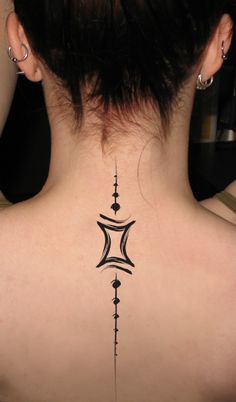 the back of a woman's neck with an intricate tattoo design on her lower back