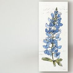 a blue flower on a white background is hanging from a wall next to a vase with flowers in it