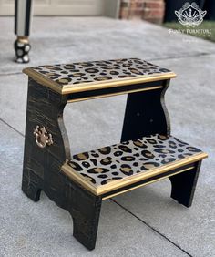 two tiered wooden step stool with leopard print on the bottom and gold trimmings