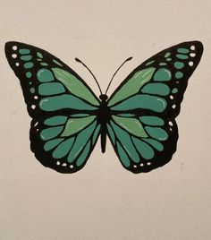 a green and black butterfly sitting on top of a white wall