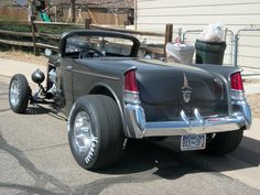 an old car parked on the side of the road in front of a fenced off building