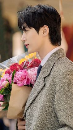 a young man holding flowers in his hand