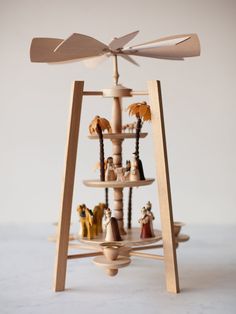 a wooden toy tower with figurines on it's sides and a wind indicator attached to the top