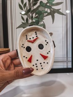 a person holding a ceramic mask shaped like a face