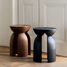 two black and brown stools sitting next to each other on top of a wooden floor