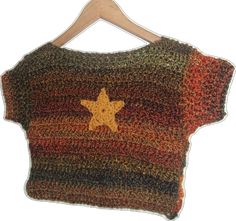 a knitted sweater with a star on the front and back, hanging from a wooden hanger